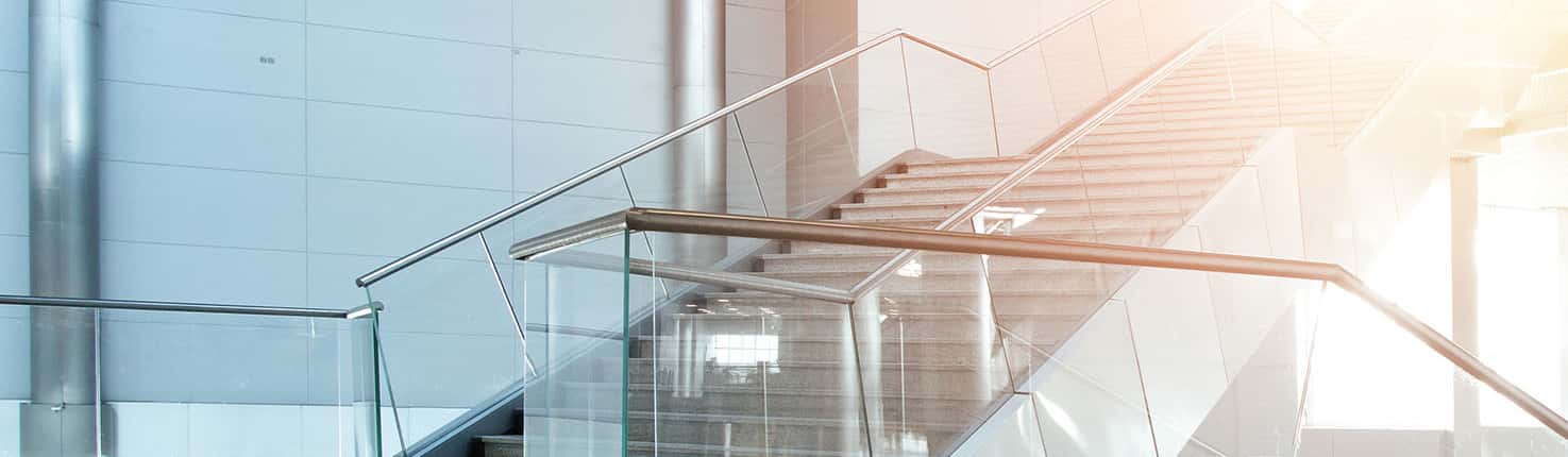 Image of a sunny staircase with glass and steel bannisters